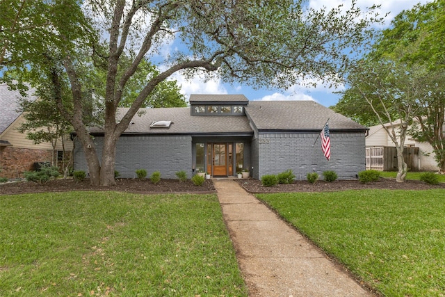 mid-century home with brick siding, a shingled roof, a front lawn, and fence