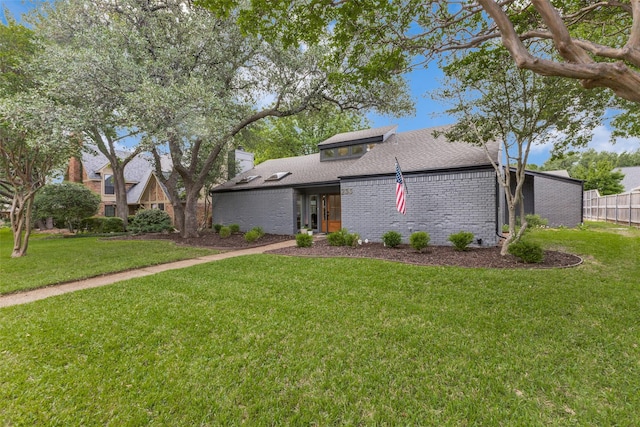 view of front of property with brick siding, fence, roof with shingles, and a front lawn