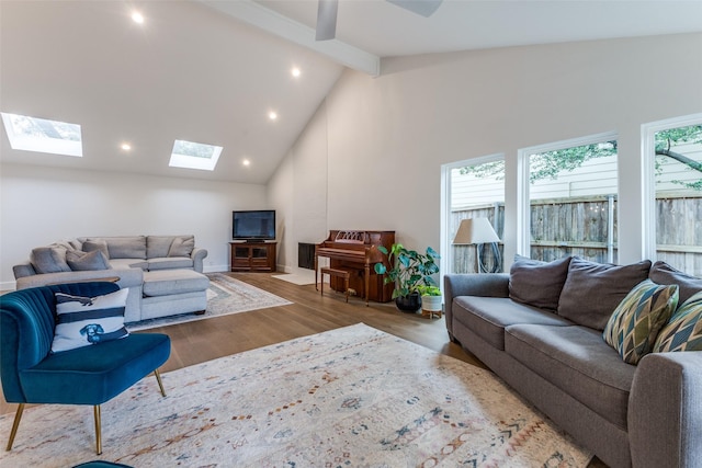 living area featuring high vaulted ceiling, a skylight, recessed lighting, wood finished floors, and beamed ceiling