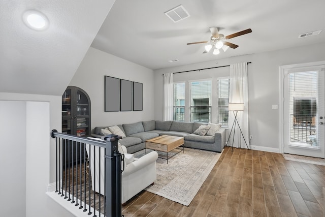 living area with a ceiling fan, baseboards, visible vents, and wood finished floors