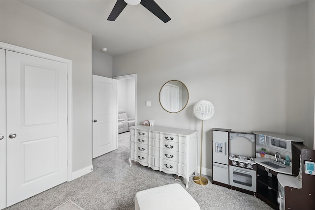 interior space with a sink, carpet floors, a ceiling fan, and baseboards