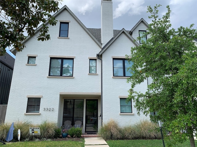 rear view of house featuring brick siding and a chimney