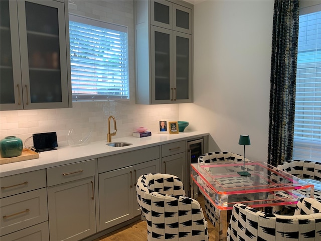 kitchen featuring a sink, decorative backsplash, light wood finished floors, and light countertops