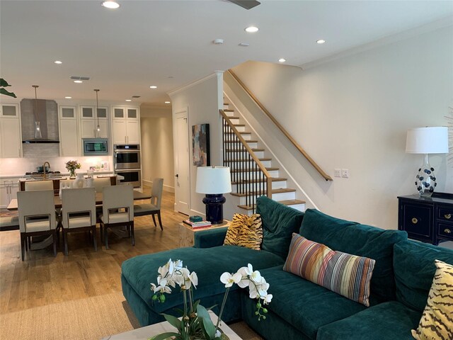 living room with light wood-style floors, stairs, recessed lighting, visible vents, and ornamental molding