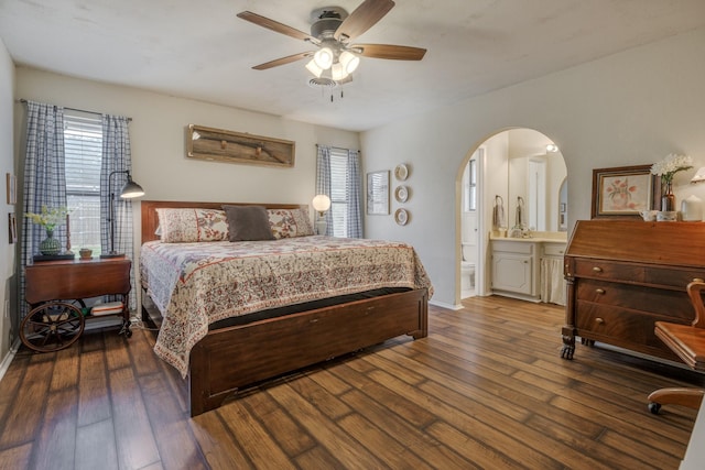 bedroom featuring connected bathroom, arched walkways, multiple windows, and hardwood / wood-style flooring