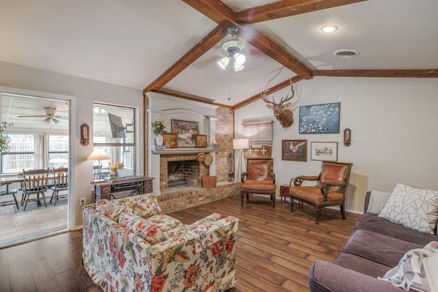 living area featuring visible vents, a fireplace, ceiling fan, hardwood / wood-style flooring, and lofted ceiling with beams