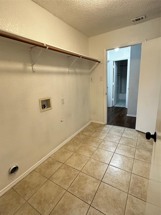 clothes washing area with a textured ceiling, hookup for a washing machine, visible vents, light tile patterned flooring, and laundry area