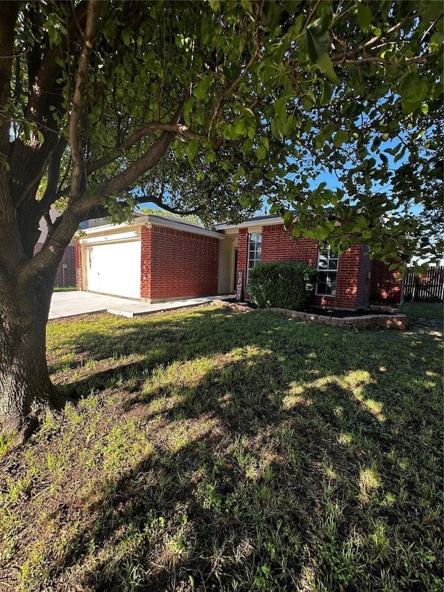 view of yard with fence, an attached garage, and driveway