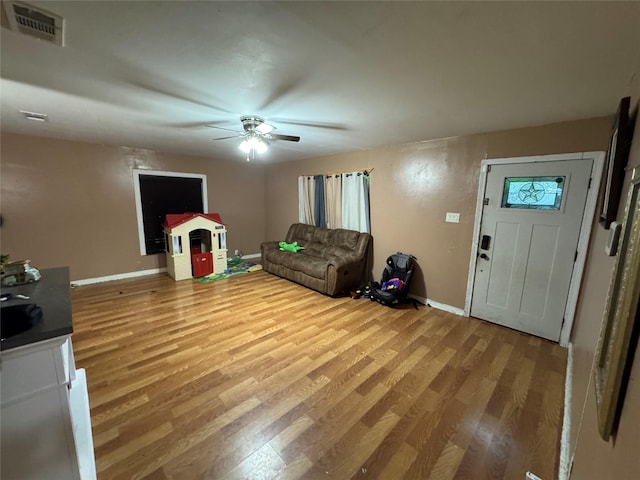 unfurnished living room with baseboards, ceiling fan, wood finished floors, and visible vents