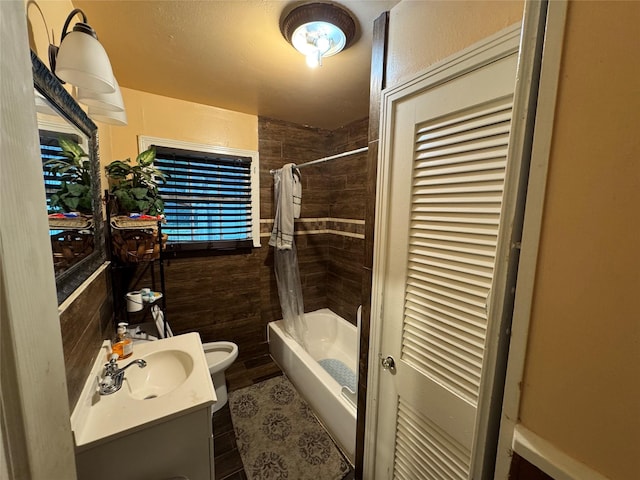 bathroom featuring vanity, toilet, shower / bathtub combination with curtain, and tile walls