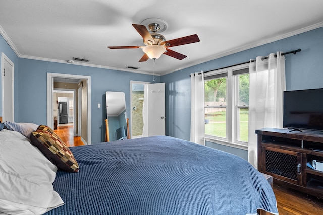 bedroom with visible vents, ornamental molding, a ceiling fan, and wood finished floors