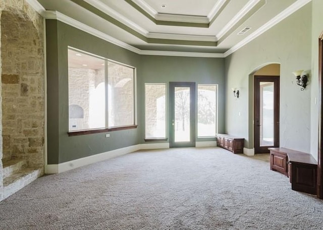 unfurnished room featuring carpet floors, arched walkways, a raised ceiling, and crown molding