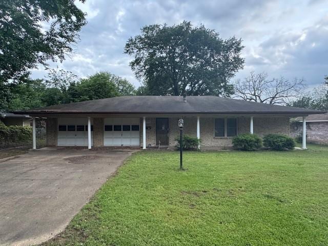 single story home featuring a garage, a front lawn, and concrete driveway