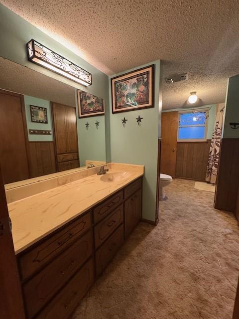 bathroom with vanity, toilet, a textured ceiling, and visible vents