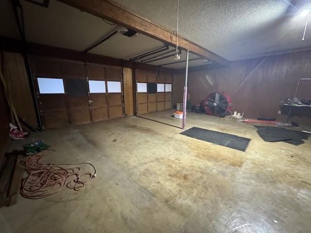 miscellaneous room with a garage, a textured ceiling, and unfinished concrete flooring