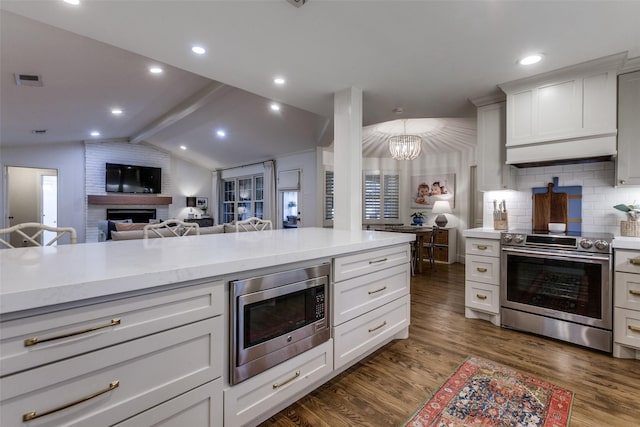 kitchen featuring light countertops, dark wood-style flooring, appliances with stainless steel finishes, and lofted ceiling with beams