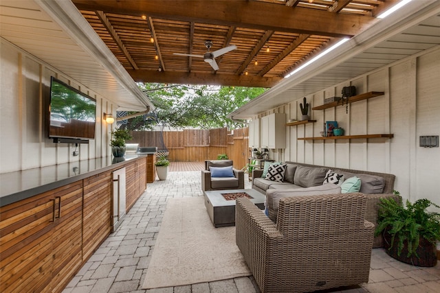 view of patio with fence, an outdoor living space with a fire pit, a pergola, and exterior kitchen