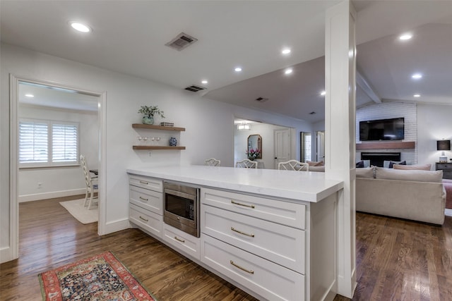 kitchen with visible vents, light countertops, stainless steel microwave, a peninsula, and open floor plan
