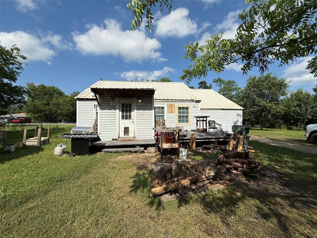 rear view of house featuring a lawn, metal roof, and a deck