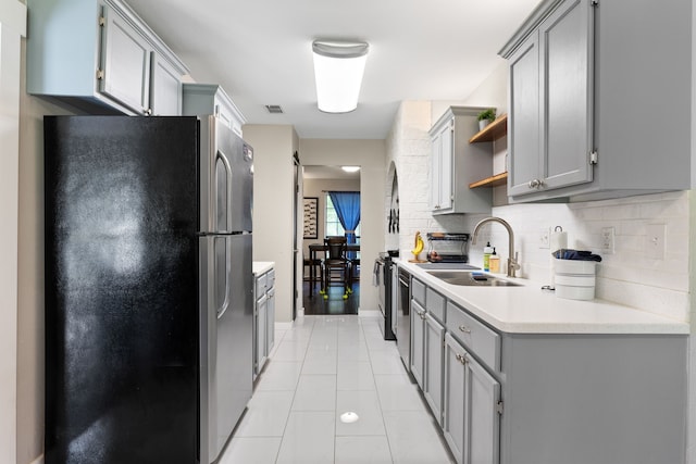 kitchen with open shelves, a sink, light countertops, gray cabinets, and freestanding refrigerator