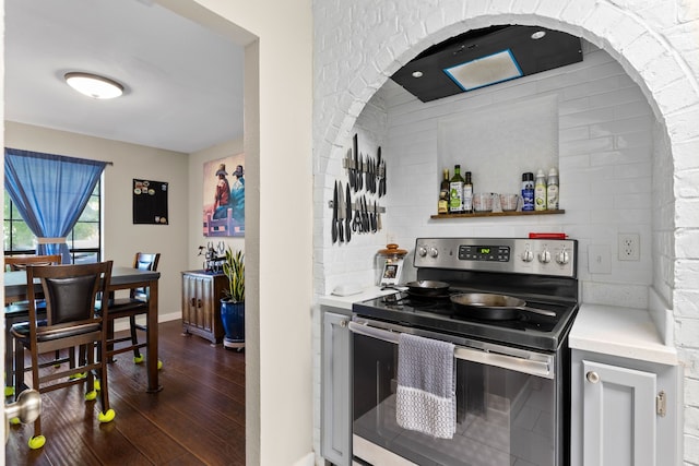 kitchen featuring light countertops, stainless steel electric range oven, baseboards, and dark wood-style floors