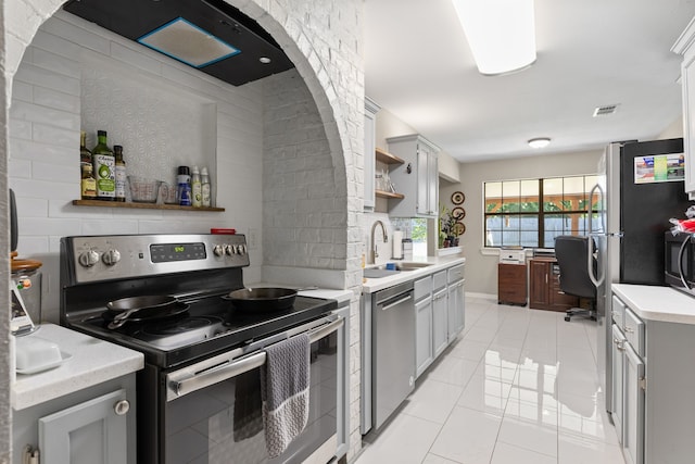 kitchen with a sink, light countertops, open shelves, and stainless steel appliances