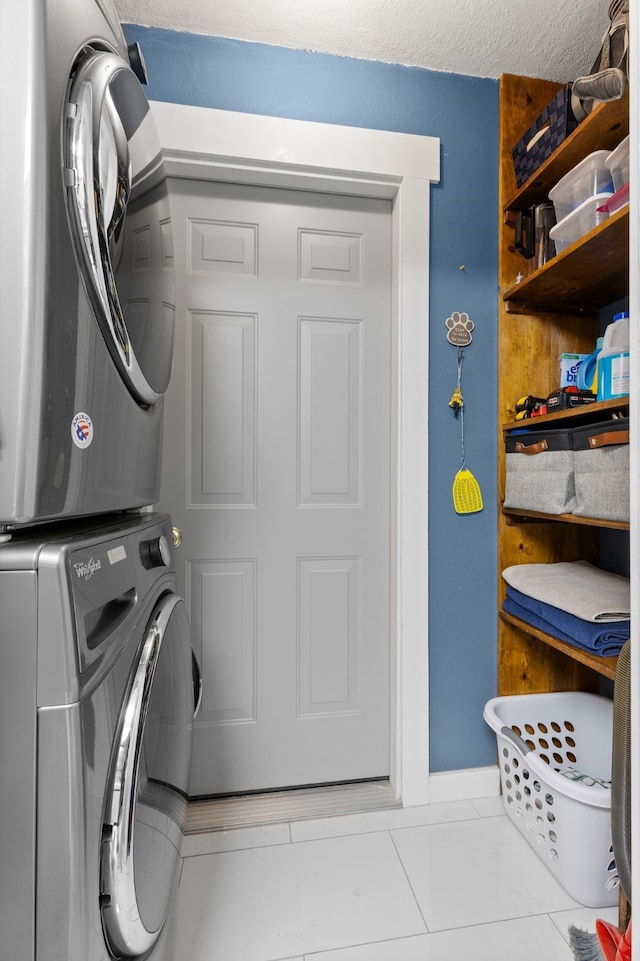 washroom with baseboards, laundry area, and stacked washer / dryer