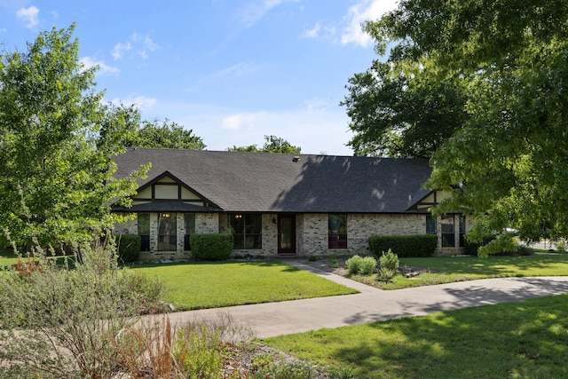 english style home with brick siding, roof with shingles, and a front yard