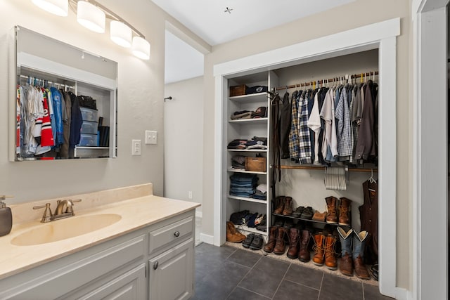 bathroom with tile patterned floors, a spacious closet, and vanity