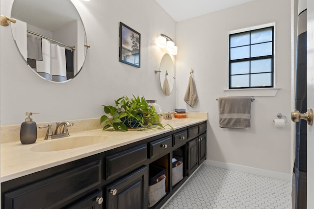 bathroom with double vanity, baseboards, and a sink