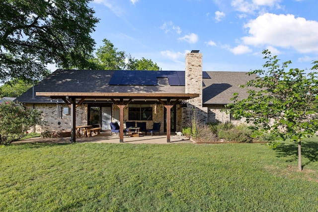 back of property with roof mounted solar panels, a chimney, a lawn, and a patio area