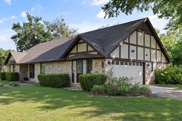 tudor-style house featuring roof with shingles, brick siding, a garage, a front yard, and concrete driveway