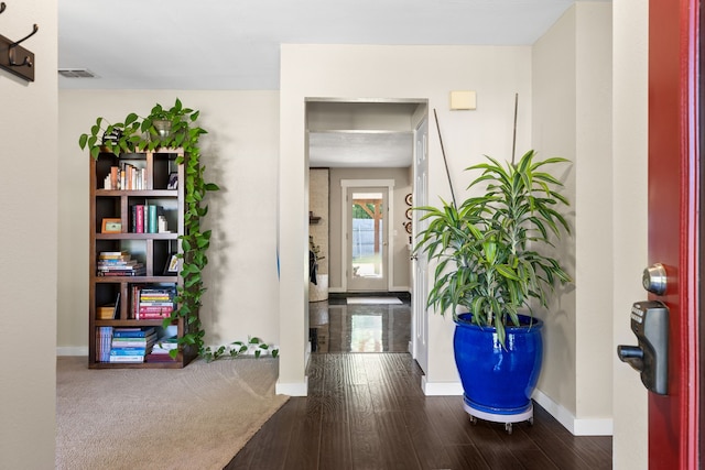foyer featuring baseboards, wood finished floors, and visible vents