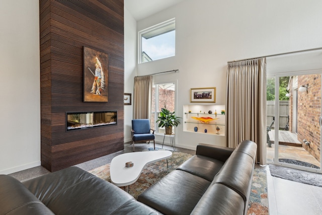 living area with a multi sided fireplace, a high ceiling, and baseboards