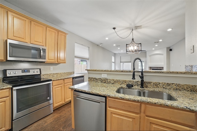 kitchen with dark wood-style flooring, light stone countertops, a notable chandelier, appliances with stainless steel finishes, and a sink