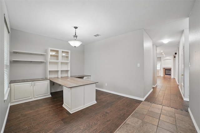 unfurnished office with visible vents, dark wood-style flooring, baseboards, and a fireplace