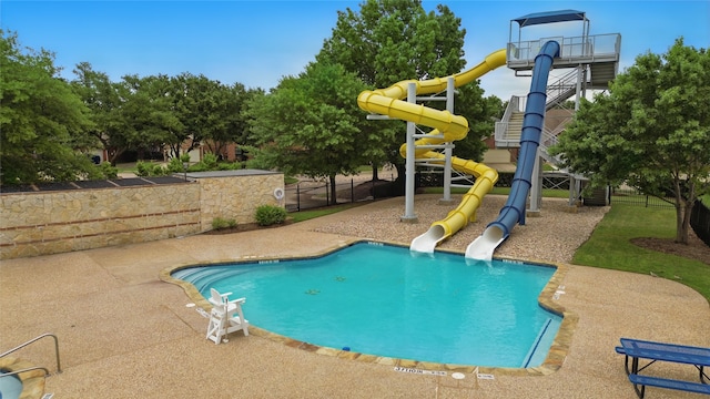 community pool featuring fence, a water slide, and a patio