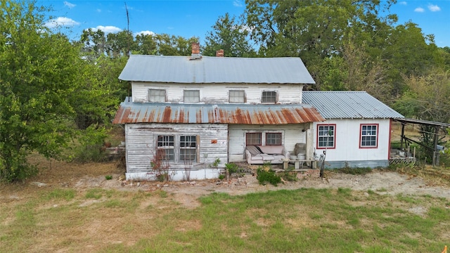 rear view of property featuring a chimney and metal roof