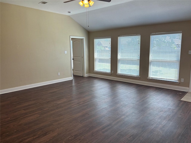 empty room with dark wood-style flooring, visible vents, a ceiling fan, baseboards, and vaulted ceiling