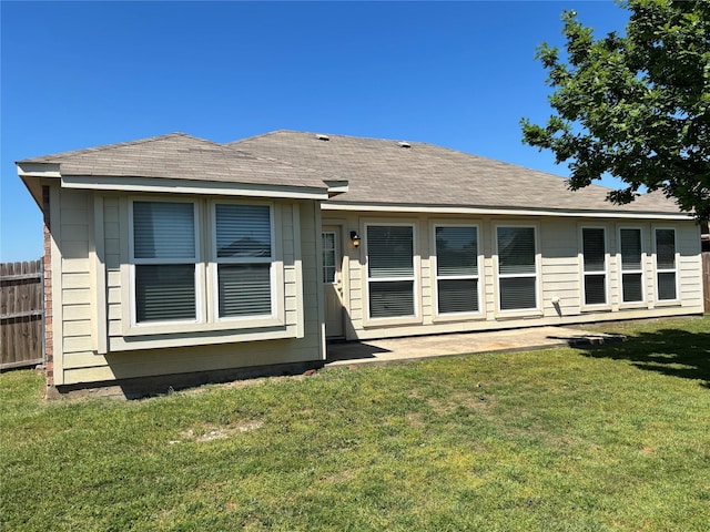 back of property featuring a lawn and fence