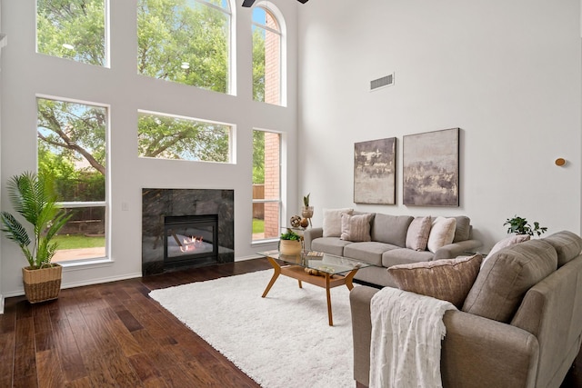 living area with a healthy amount of sunlight, a high ceiling, and dark wood-style floors