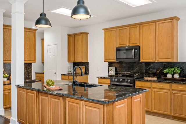 kitchen featuring decorative backsplash, decorative columns, a center island with sink, a sink, and gas stove