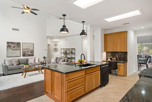 kitchen with visible vents, dishwasher, a sink, open floor plan, and dark stone counters