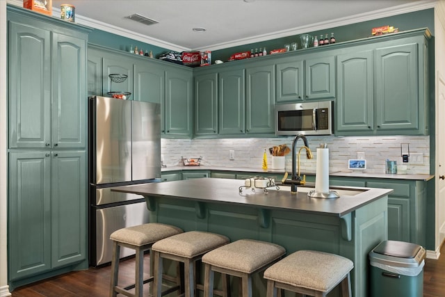 6510 Circo Dr, Granbury, TX 76049 - kitchen featuring stainless steel appliances, green cabinetry, dark wood-style flooring, crown molding, and a breakfast bar area