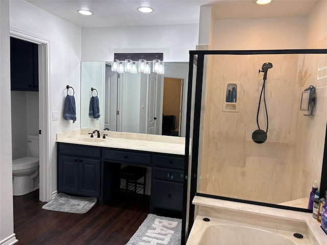 bathroom with a stall shower, a bathtub, toilet, vanity, and wood finished floors