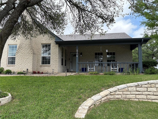 back of property with a shingled roof, brick siding, and a lawn
