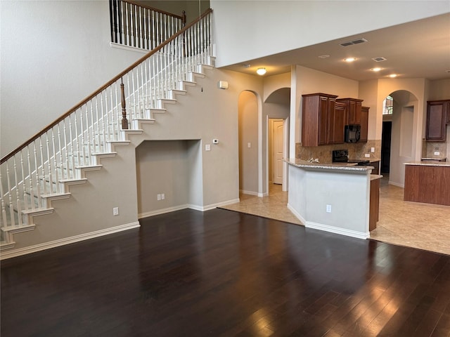 1121 Albany Dr, Fort Worth, TX 76131 - kitchen featuring a towering ceiling, visible vents, arched walkways, wood finished floors, and black appliances