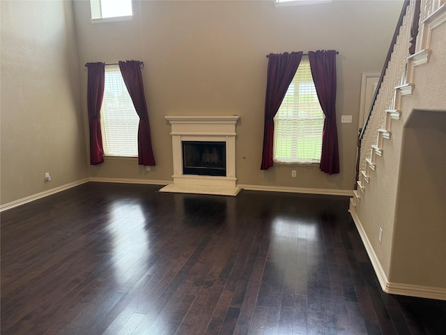 1121 Albany Dr, Fort Worth, TX 76131 - unfurnished living room with a healthy amount of sunlight, a fireplace with raised hearth, stairs, and hardwood / wood-style floors