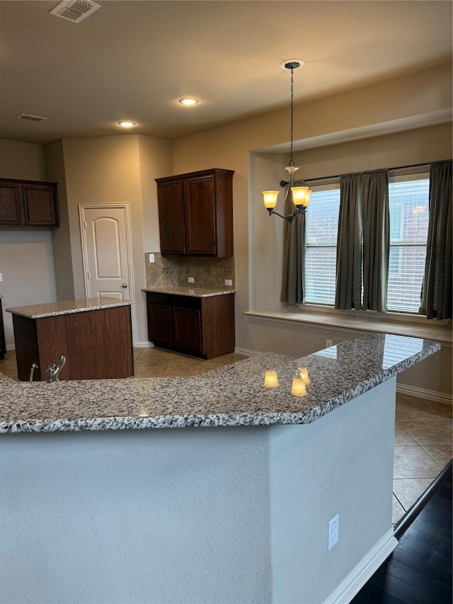 1121 Albany Dr, Fort Worth, TX 76131 - kitchen featuring an inviting chandelier, backsplash, light tile patterned floors, and light stone countertops