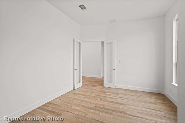 empty room featuring baseboards, light wood finished floors, and visible vents